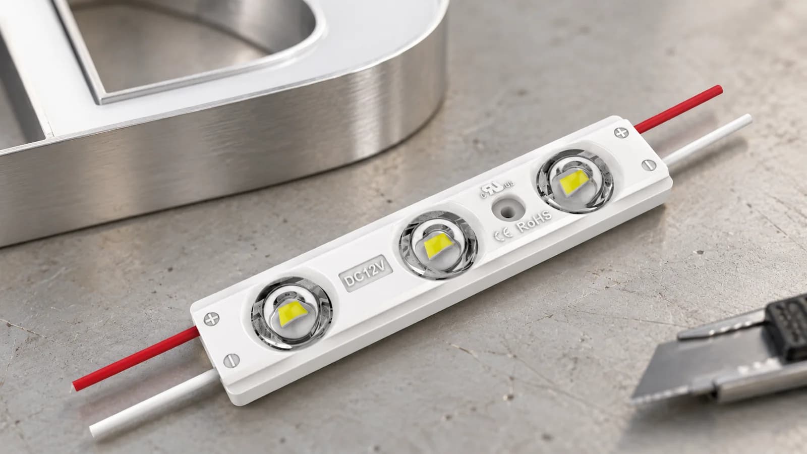 Detalle de un módulo LED de tres lentes para letreros en una mesa de trabajo